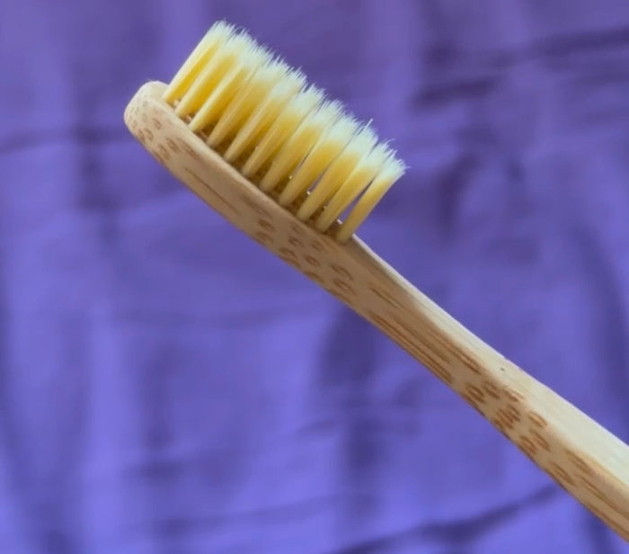 Hand dripping oil onto a bamboo brush.